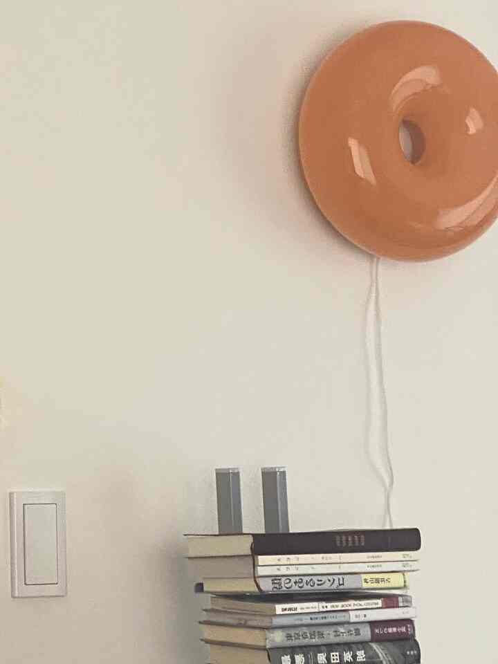 White-walled dressing room with a stack of books and an orange table lamp creating a natural, cozy atmosphere