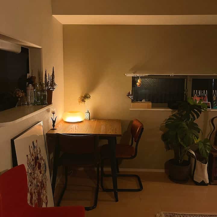 Warm wood tone dining room featuring indirect lighting, a Slam Dunk poster, and lush plants in a cozy setting