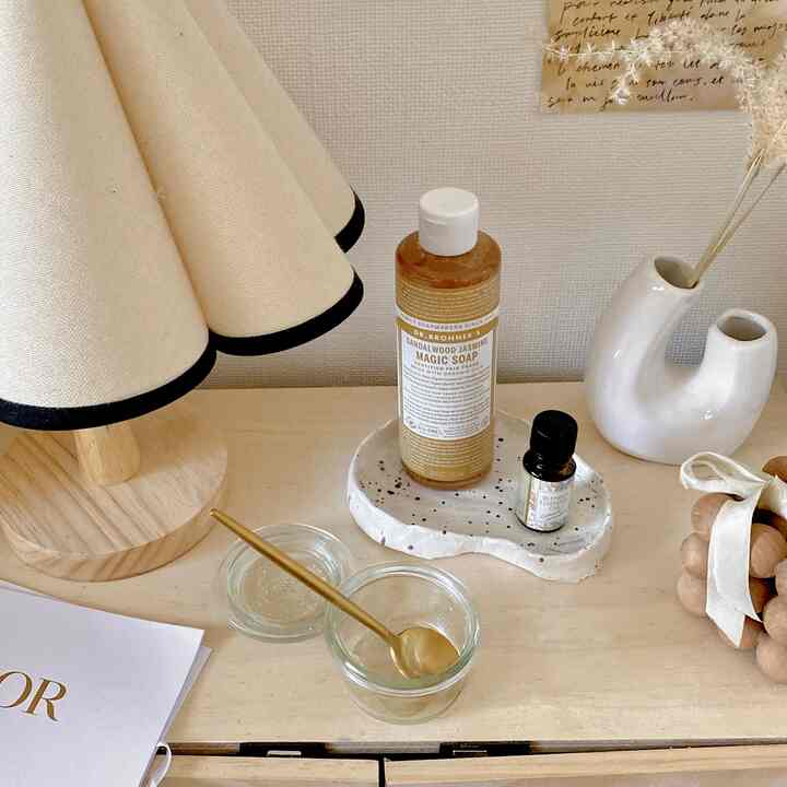 明るい木目調テーブルにゴールドスプーンとディフューザー、ナチュラルカラーの照明が配置された雰囲気ある寝室のインテリア