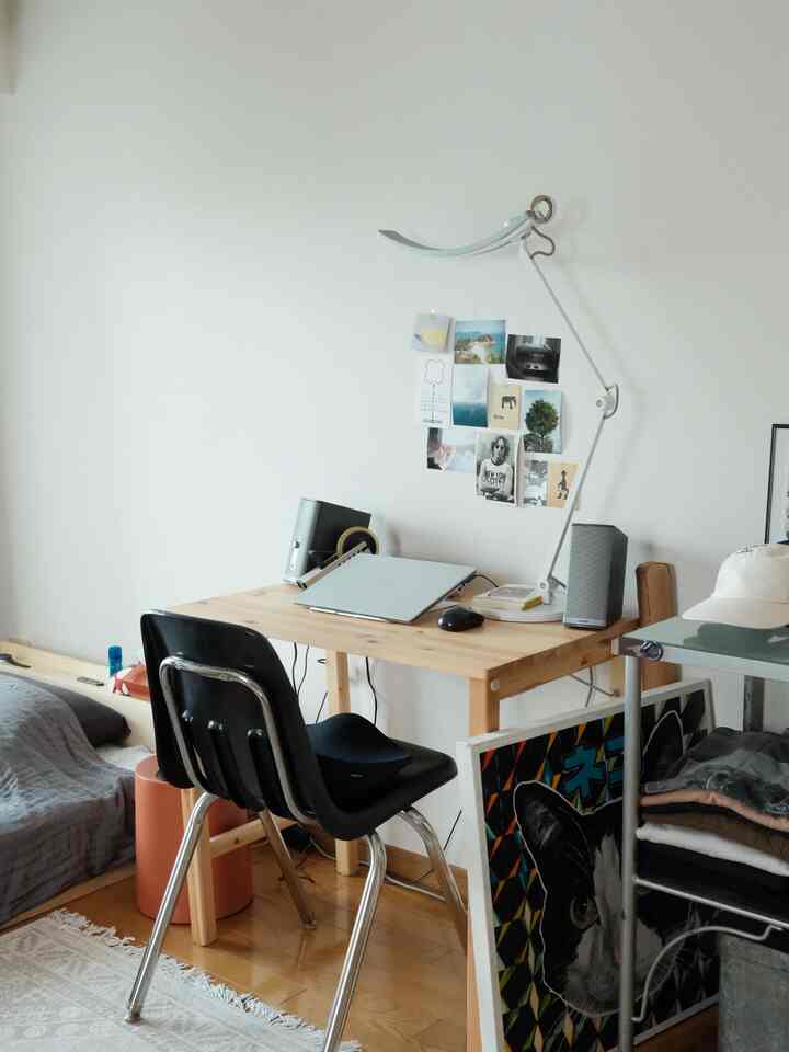 ナチュラルな色調の小さな部屋に木製のデスクと黒いオフィスチェアが配置された落ち着いたホームオフィス