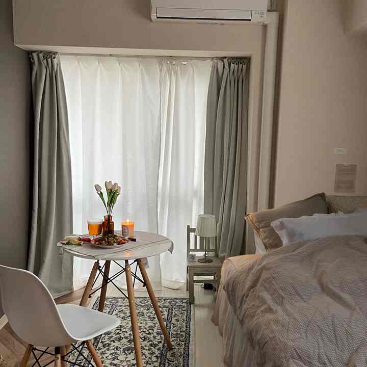 Beige and white toned bedroom featuring a round table and chair, creating a simple and natural atmosphere