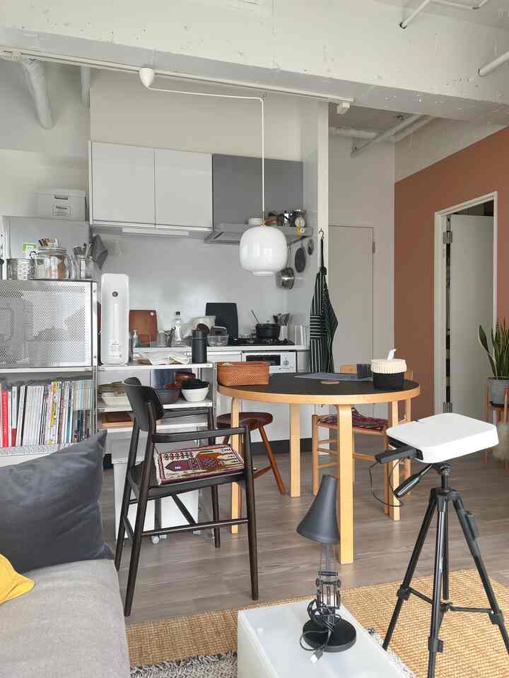 Modern kitchen and dining room with white and wood tones, featuring armchair and tidy storage in a cozy setting