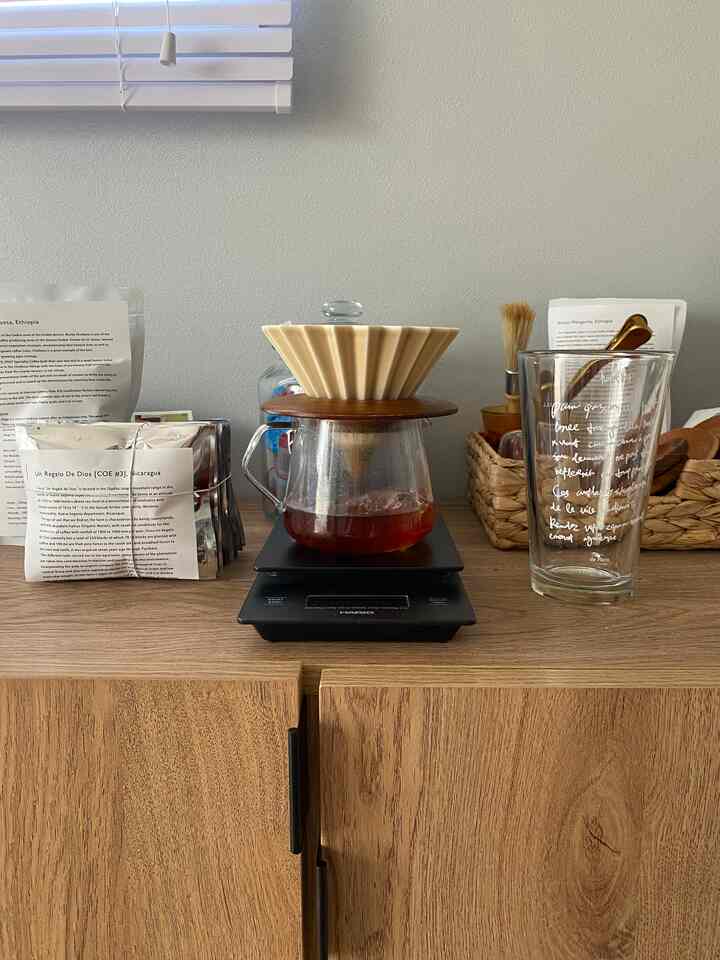木目調のナチュラルなトーンのホームカフェ、ドリップコーヒーセットと透明なグラスが置かれた温かみのある空間