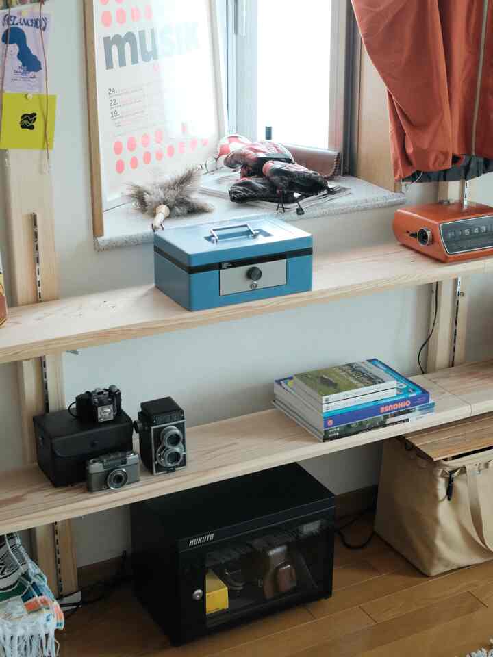 Natural wood tone shelves and white walls in a hobby room, various items placed on the window sill