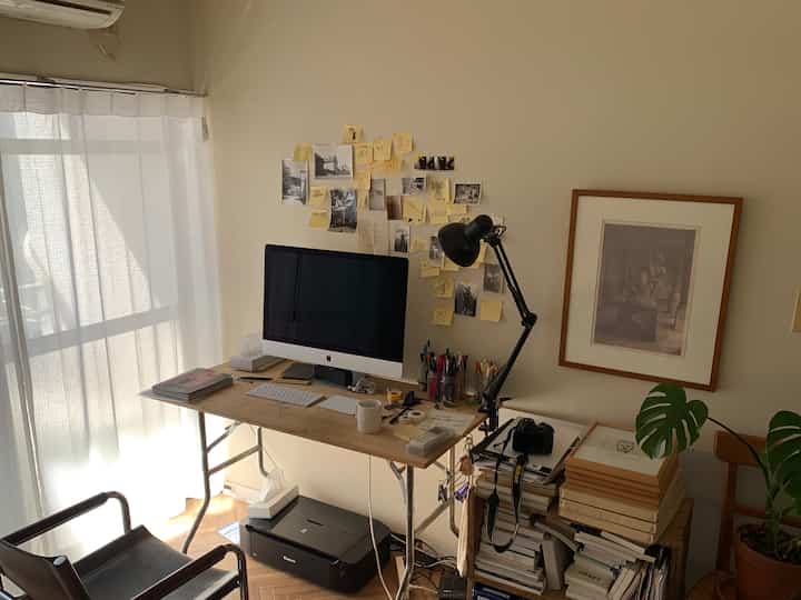 Cozy home office space with white walls and a brown wooden desk, featuring a computer and a table lamp creating a harmonious atmosphere