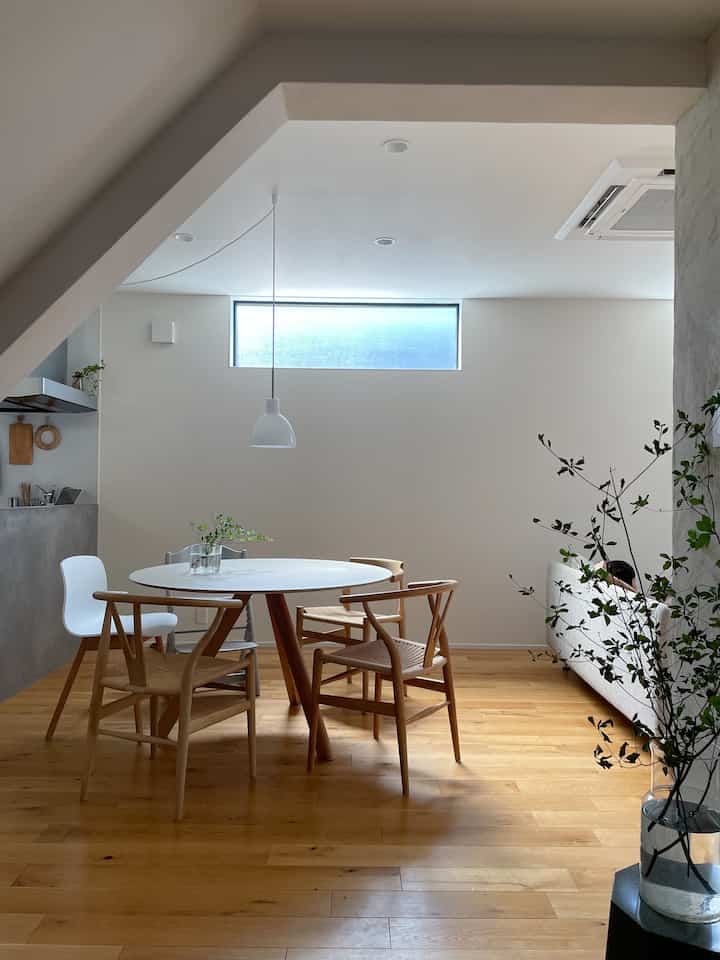 ナチュラルな色調のダイニング、丸いテーブルと木製の椅子が配置された温かみのある清潔な空間