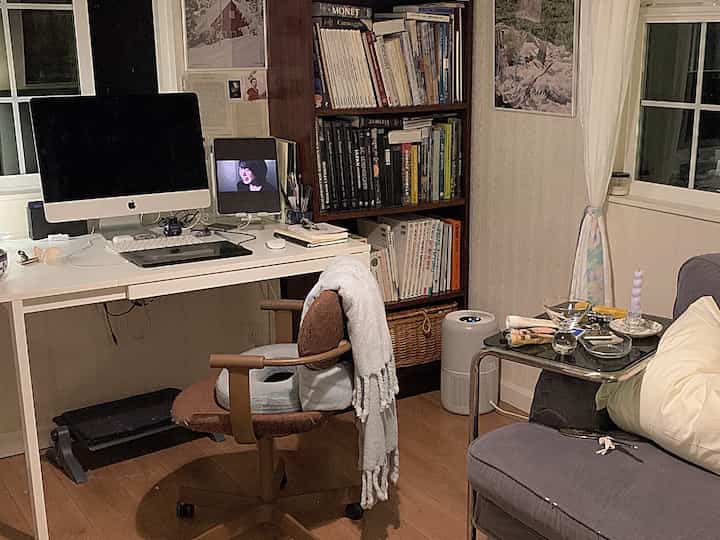 白と茶色のトーンのホームオフィス兼リビング、机と椅子、本棚が配置された居心地の良い作業空間