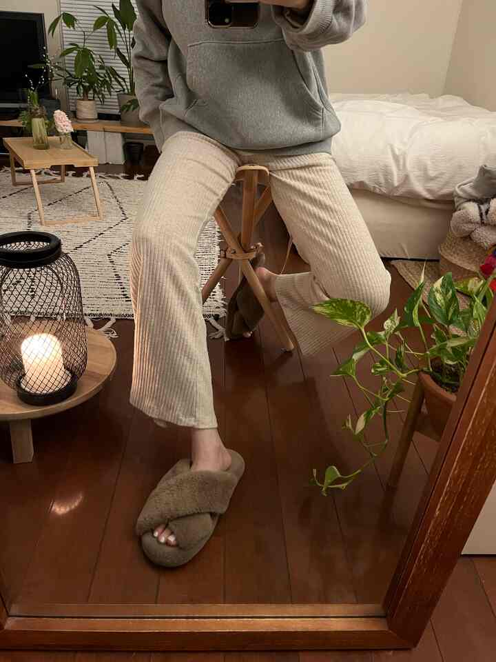 ナチュラルな木目調の床と植物がある暖かいトーンの寝室、白い寝具とラグが配置された雰囲気のある空間