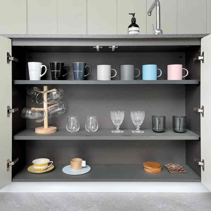 グレーと白の調和が美しい実用的なキッチンキャビネット、様々なマグカップとグラスが整然と並ぶ印象的な空間