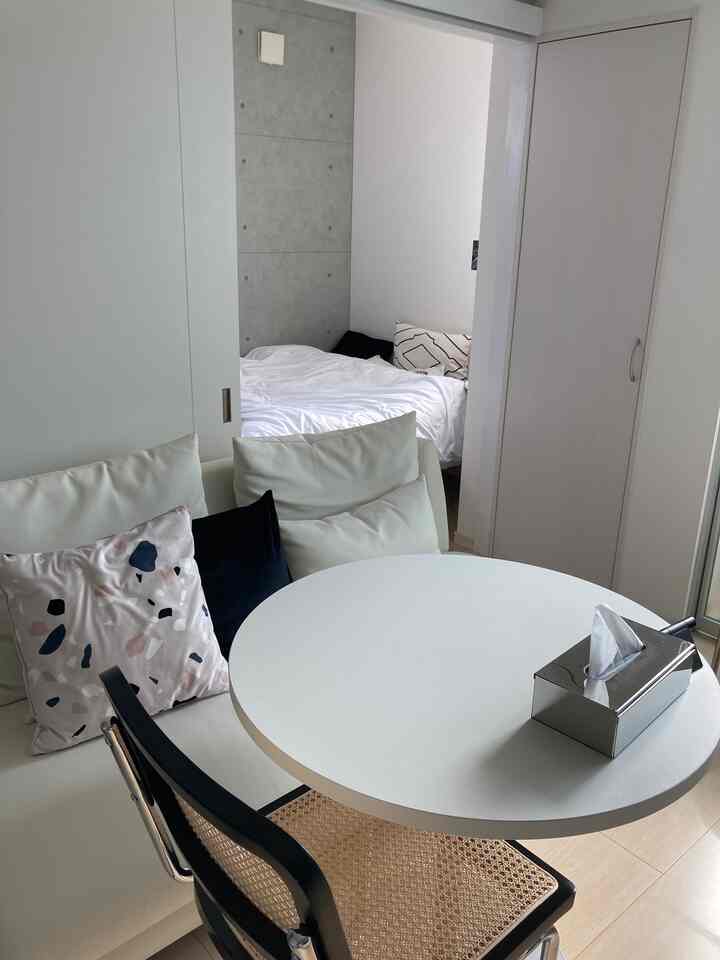 White-toned living and dining room featuring a round table and sofa with a simple, compact atmosphere