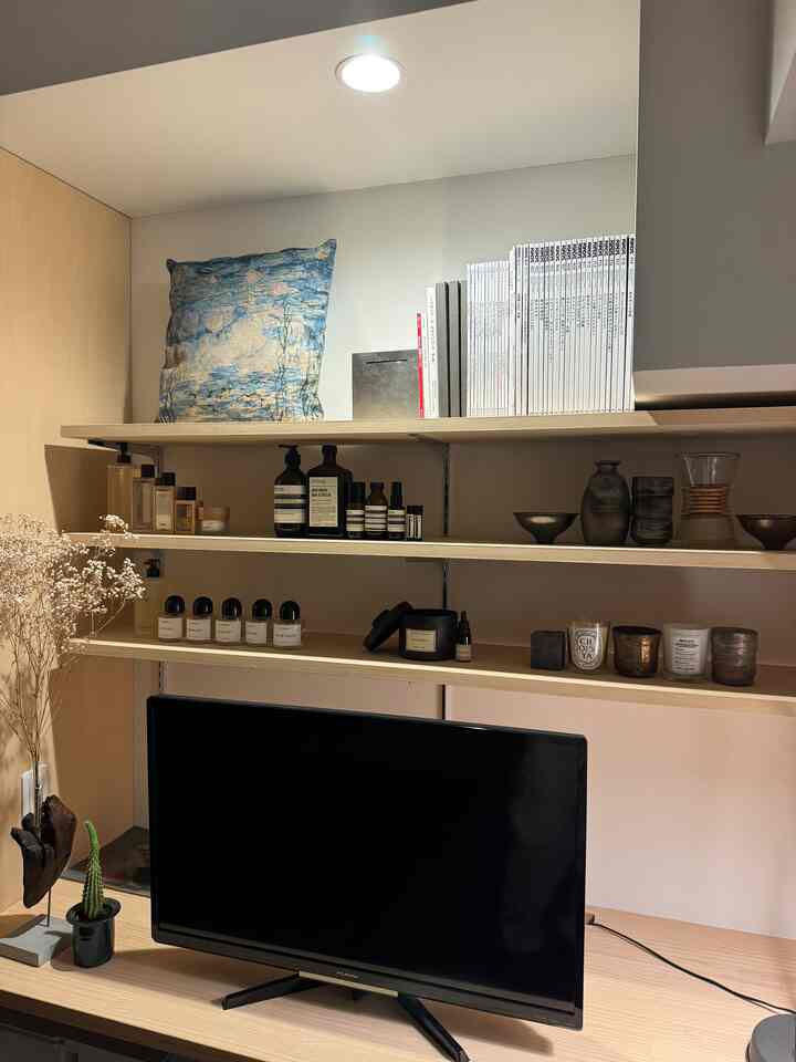 White and wood tone single household home office, with desk and bookshelf neatly arranged in a minimal space
