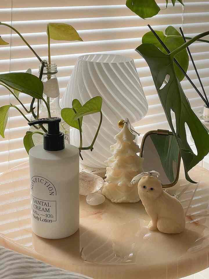 白を基調としたテーブルにソイキャンドルとボディローション、植物が配置された雰囲気のあるインテリア