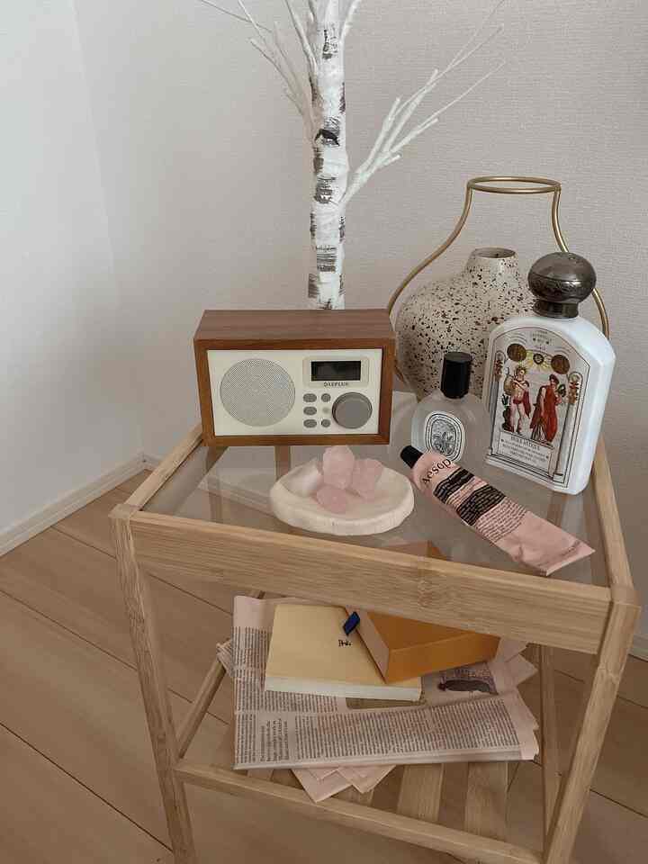 Natural tone walls and floor with a wood-colored side table holding a radio, diffuser, and candle in a cozy living room