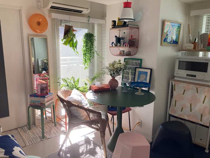 グリーンのトーンとナチュラルスタイルの小さなダイニングルーム、丸いテーブルとラタンの椅子が配置された暖かみのある空間