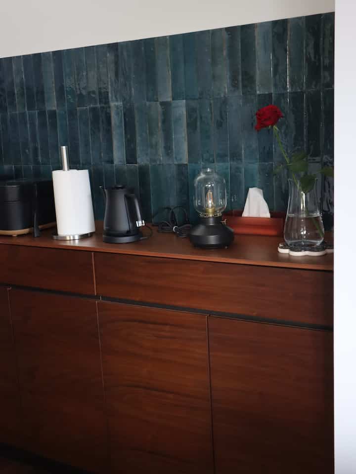 木目調と黒のアクセントが調和したキッチン、テーブルランプと赤いバラが飾られた洗練されたサイドボードのインテリア