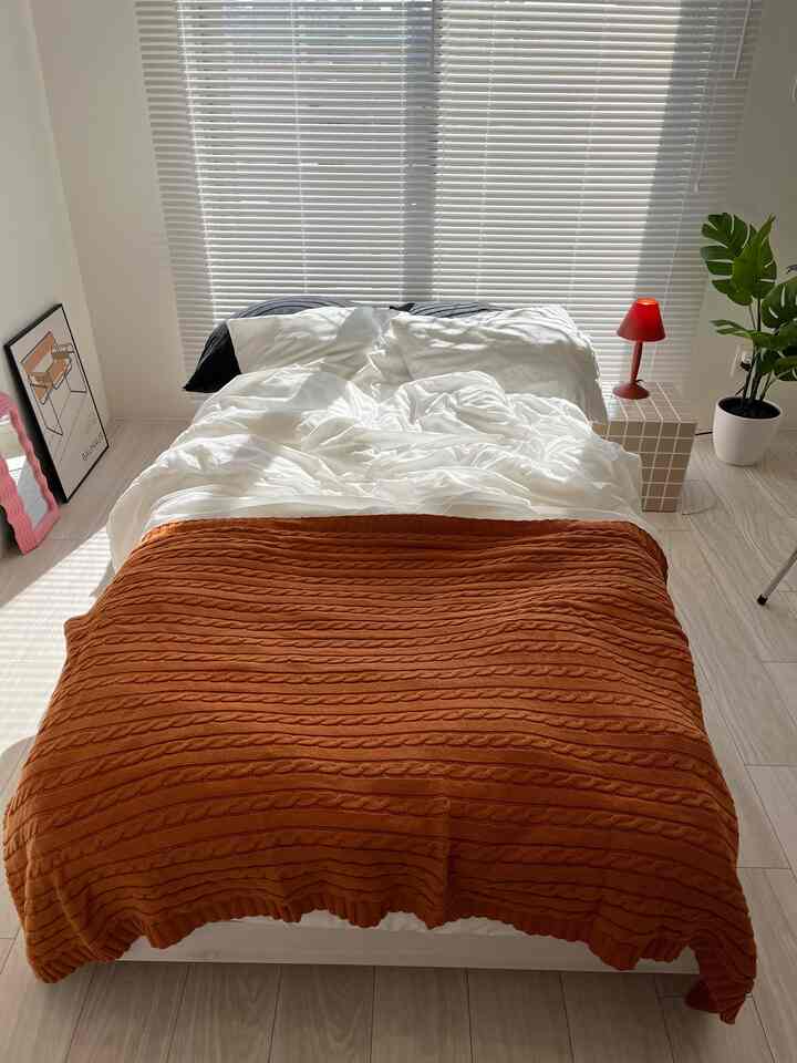 白と茶色の寝室、中央にベッドとキャメルカラーのブランケットが置かれたモダンでシンプルな印象的な空間