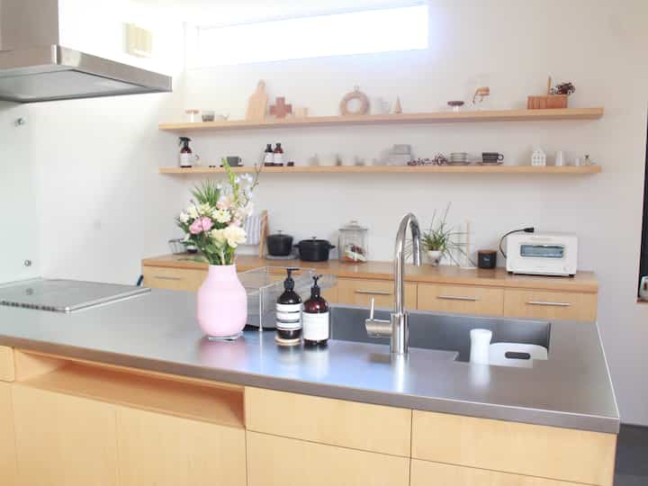 ウッドトーンと白を基調としたキッチン、中央にピンクの花瓶とディフューザーが配置されたシンプルで清潔感のあるインテリア