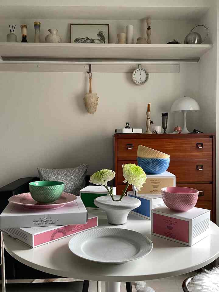 白とナチュラルトーンのキッチン、カラフルなボウルと皿がシンプルなテーブルに整然と配置された雰囲気のあるインテリア