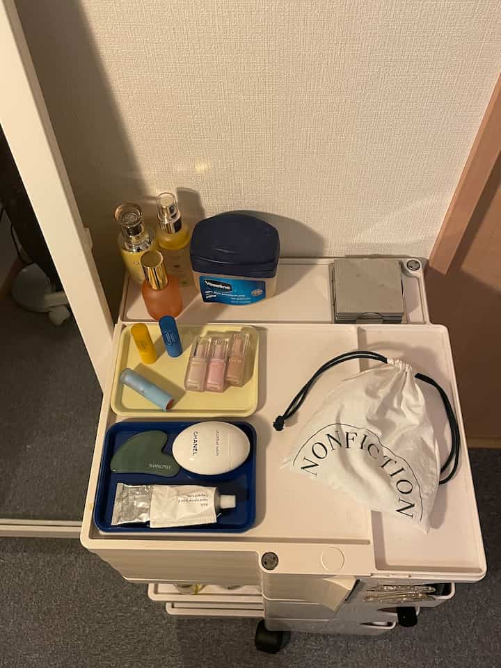ホワイトとブルーの色調の一人暮らし空間、ボビーワゴンの上にトレイと化粧品が整然と配置された印象的な収納スペース