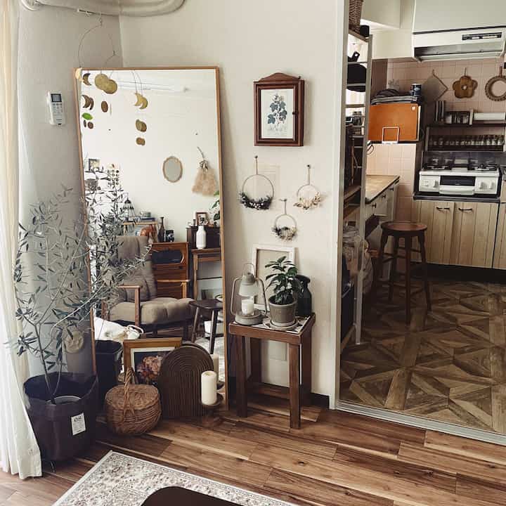 ナチュラルな木目調のリビング、 大きな鏡と植物、居心地の良いアームチェアが配置された雰囲気のあるインテリア