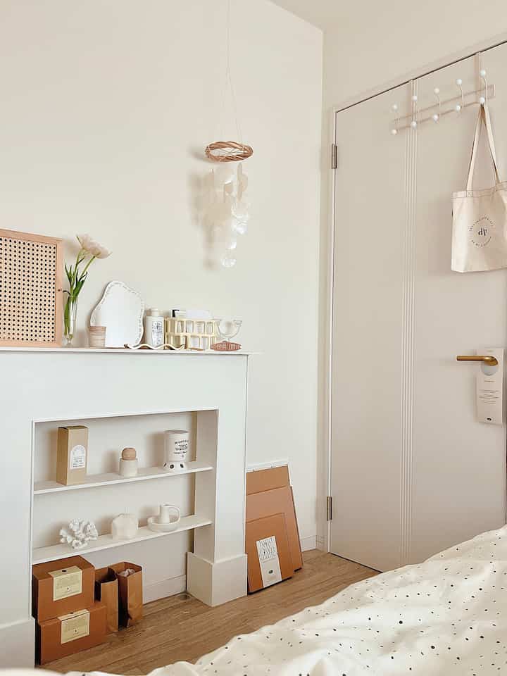 白とベージュのトーンの寝室、ドット柄の掛け布団カバーとキャンドル飾りが配置されたミニマリズムなインテリア