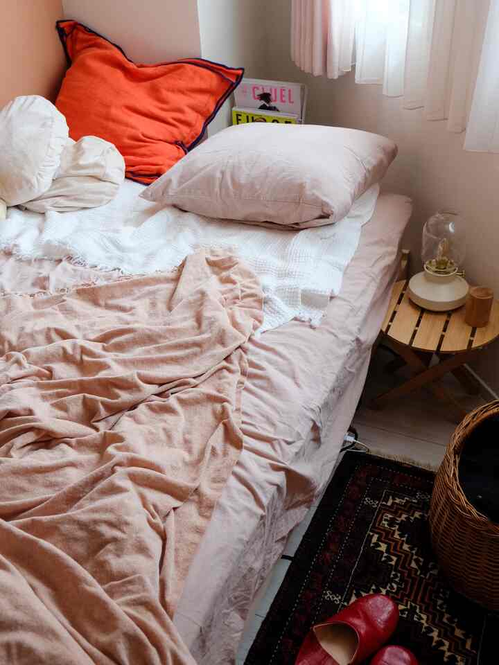 ベージュトーンの寝室、枕とスローが配置された落ち着いたモダンな空間