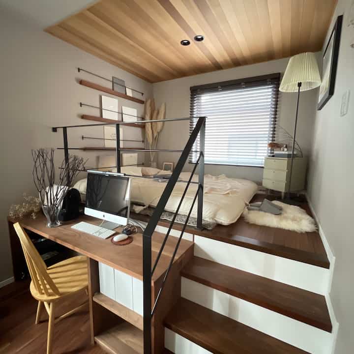 Natural wood-toned bedroom featuring a brown desk and loft-style futon sleeping area with a cozy atmosphere