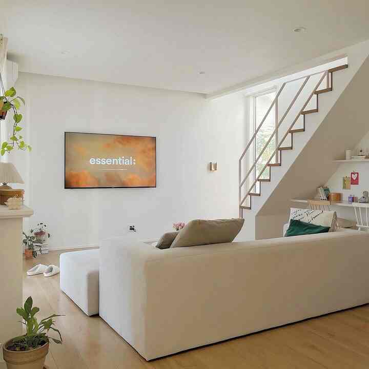 ナチュラルカラーとホワイトトーンのリビング、階段下に置かれた大きなソファと勉強スペースがある雰囲気のあるインテリア