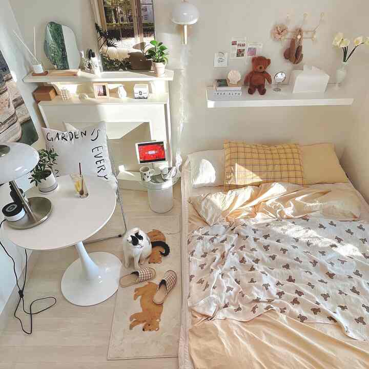 Natural and white toned bedroom featuring a bed, round table, and a cat on a rug creating a cozy atmosphere