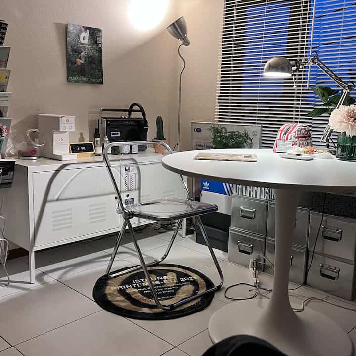 白を基調としたモダンなワンルーム、丸いダイニングテーブルと透明な椅子が置かれた狭い空間