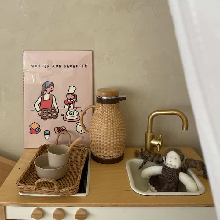 ナチュラルな木目調とベージュの暖色系が調和した子供部屋に、キッチンおもちゃセットと人形が置かれた雰囲気のあるインテリア