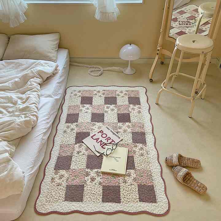 Beige and white toned bedroom space featuring a quilted rug and pillows with a tidy atmosphere