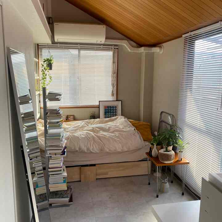 白と木目調の4.5畳寝室、本棚、全身鏡、植物が配置された雰囲気のあるミニマルな空間