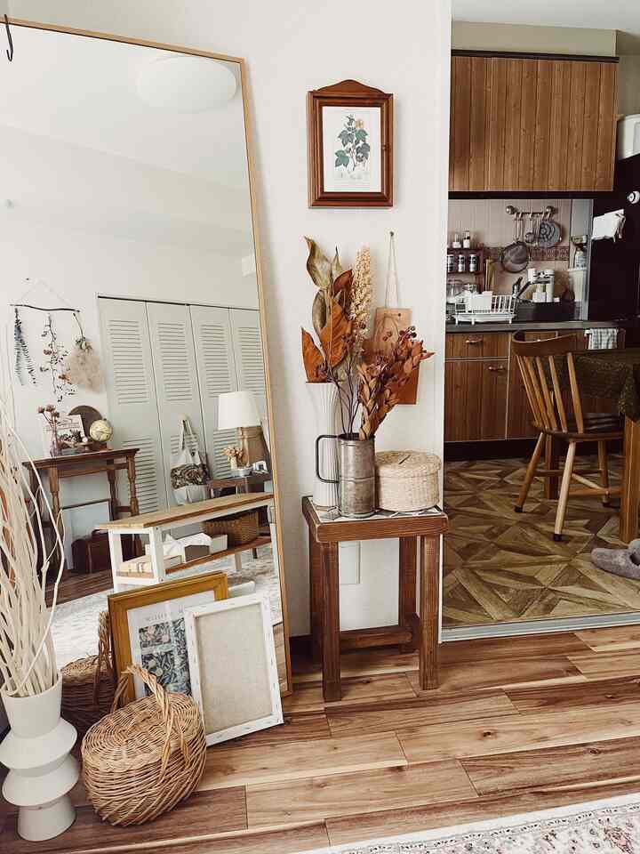 Natural wood tones and white walls in a living room and kitchen space featuring a large mirror and dining chair for a warm atmosphere