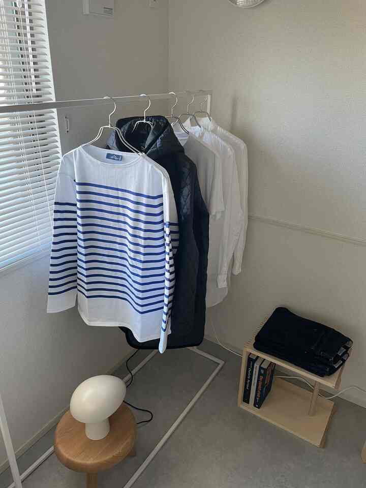 ホワイトとウッドトーンのコンパクトな部屋、テーブルランプとサイドテーブルが配置されたミニマルで雰囲気のあるインテリア