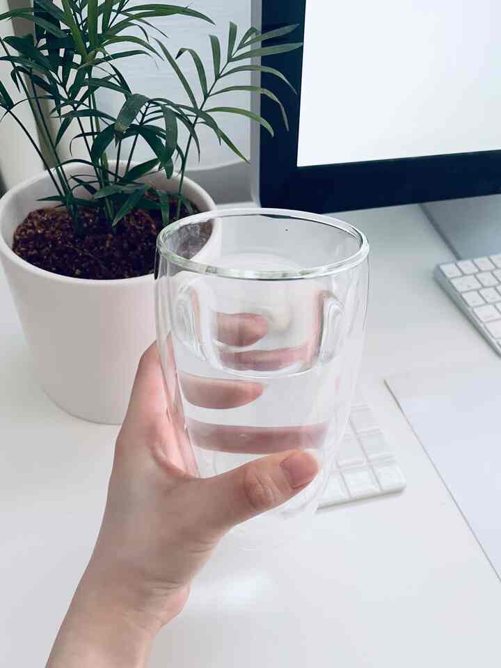 ナチュラルカラーのホームオフィス、透明なダブルウォールグラスと白いデスクに置かれた緑の植物が調和する清潔感のある空間