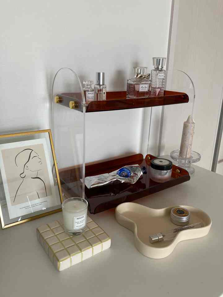 白と茶色のトーンでまとめられたテーブルの上に透明なアクリルの2段トレイと小物が置かれたミニマルでナチュラルな雰囲気のインテリア