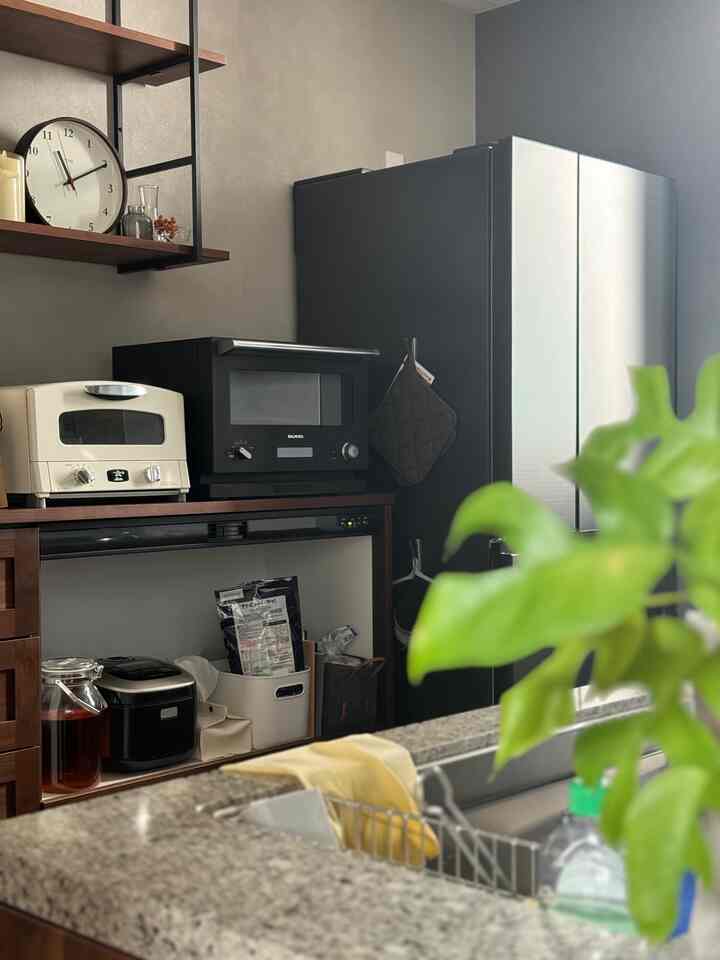 ブラウン木製と黒の家電が調和するモダンなキッチン、整理された小物が配置された印象的な空間