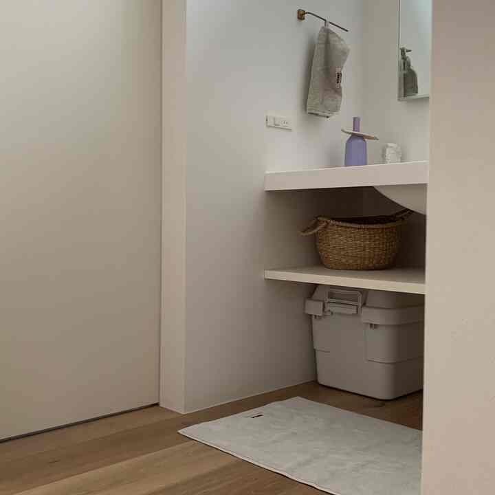 白とナチュラルカラーのバスルーム、テクラのバスマットとタオルが配置されたすっきりとした印象のインテリア