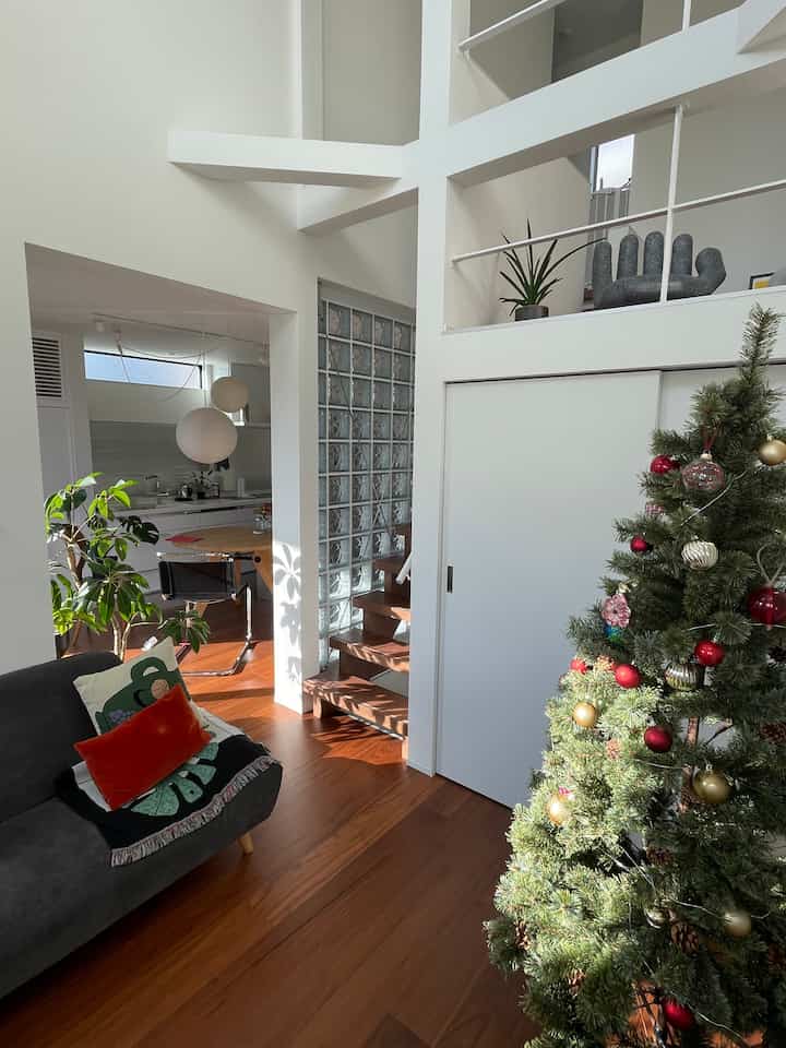 白と茶色のトーンのリビング、クリスマスツリーとソファが配置された明るく清潔な雰囲気のインテリア