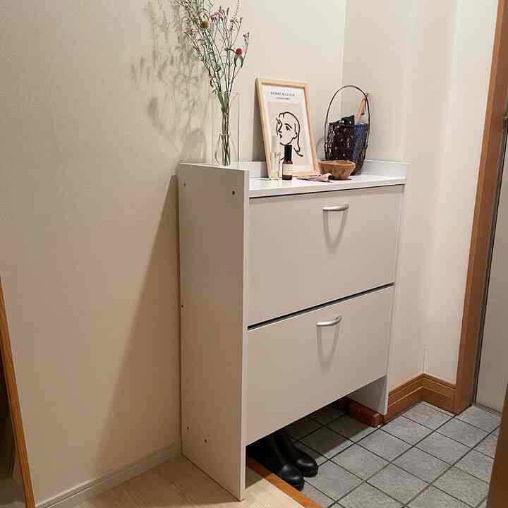 白を基調とした玄関、コンパクトで実用的なシューズラックが置かれた雰囲気のあるインテリア