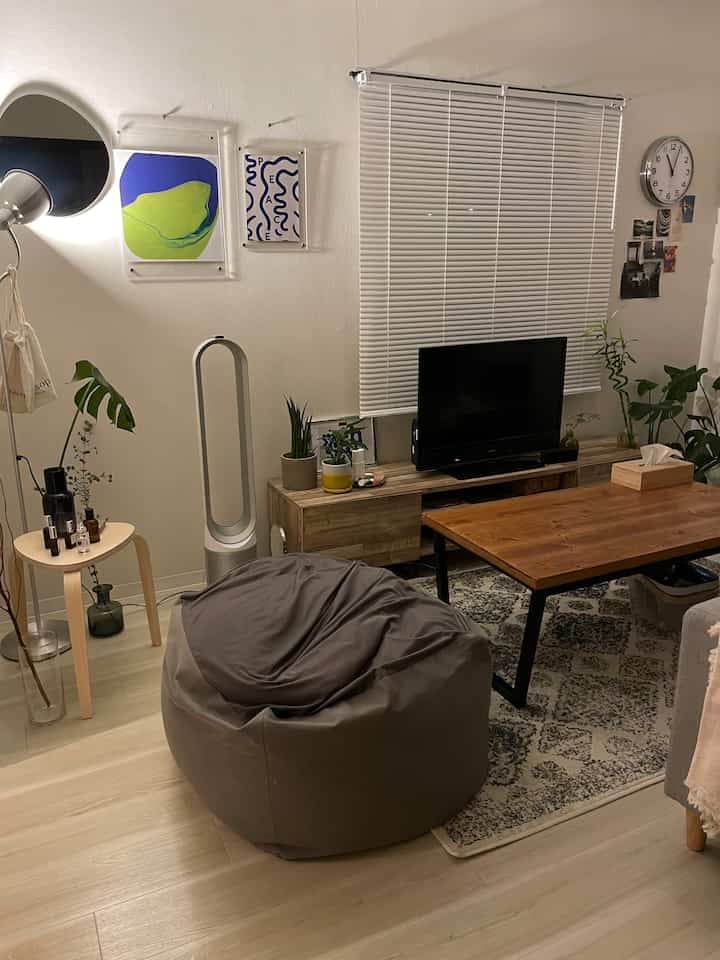 Modern living room with wood tones featuring a bean bag, coffee table, and blinds creating a cozy ambiance