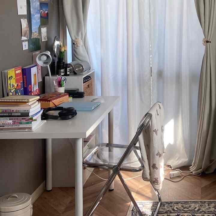 白とベージュの色調のホームオフィス、透明な折りたたみ椅子とデスクが配置された落ち着いた作業空間