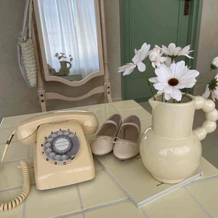 黄色の温かみある空間、花瓶とヴィンテージ電話が配置された自然な雰囲気のインテリア