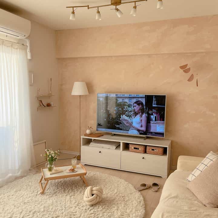 Natural beige-toned living room featuring a sofa, rug, TV stand with a cozy and comfortable atmosphere