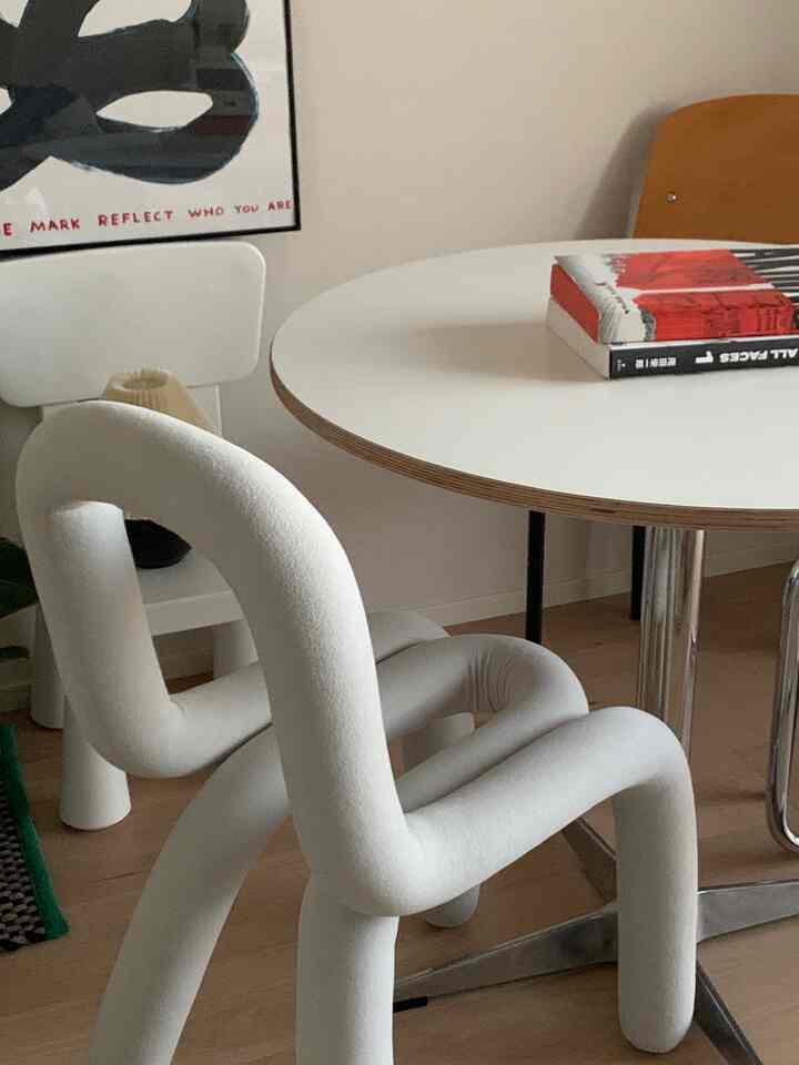 White-toned dining table with uniquely curved chair in a modern two-person household space