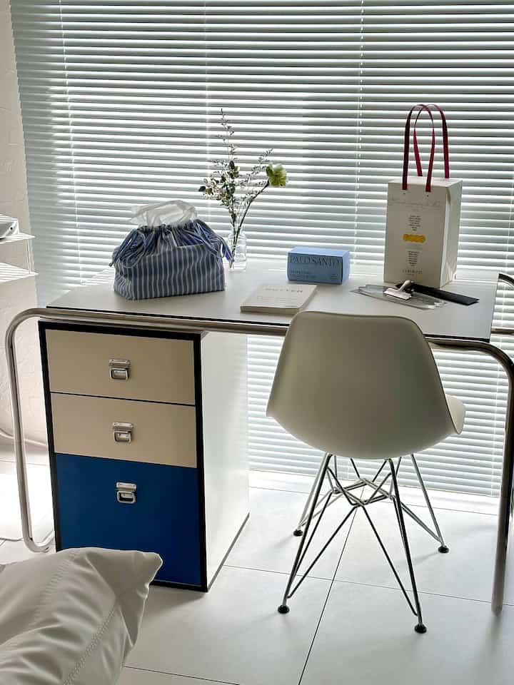 White and blue toned home office featuring a modern desk and chair with a clean and practical interior atmosphere