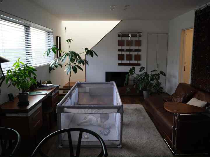 ブラウンのソファと赤ちゃんの遊び場が配置されたナチュラルなリビングインテリア