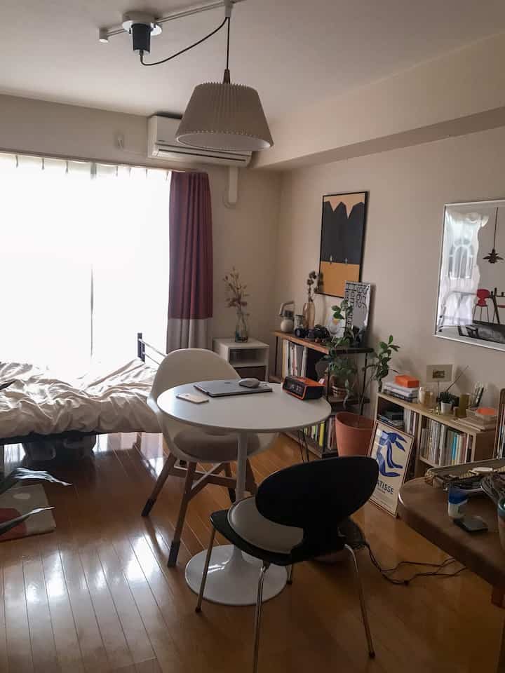 Beige-toned single household room featuring a round white table with mixed chairs in a cozy natural cafe-style interior