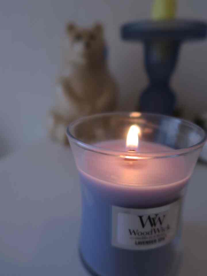 ラベンダーの香りのキャンドルが灯され、白を基調とした小さな洗面所に配置された落ち着いた空間